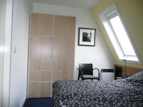 霍勒姆Kaapshoff 32的一间卧室设有一张床、一个窗口和一把椅子
