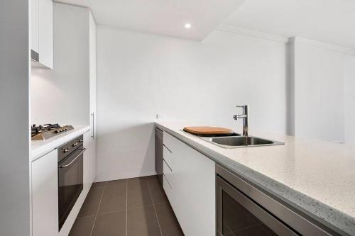 悉尼Panoramic City View 3bed2bath condo Wi-Fi Parking的白色的厨房设有水槽和台面