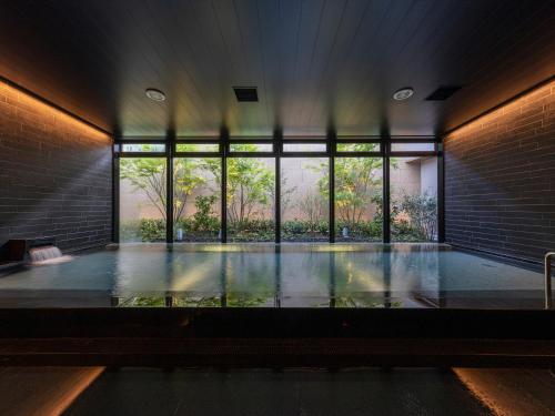 熊本THE BLOSSOM KUMAMOTO的客房设有带大窗户的游泳池