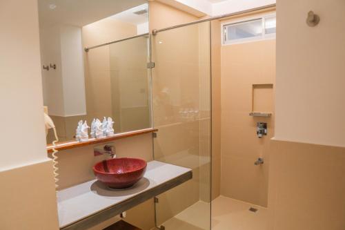 长滩岛The Paragon Boracay Suites的浴室设有玻璃淋浴间,在柜台上放着红色碗