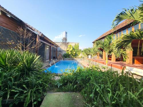 邦美蜀T'Farmstay villa and resort Buon Ma Thuot City的一座游泳池,位于一座建筑旁的院子内