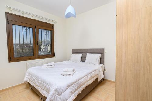 亚历山德鲁波利斯4 Seasons Home的一间卧室配有一张带白色床单的床和一扇窗户。