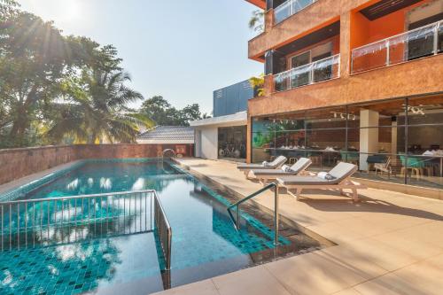 戈阿韦尔哈Aiden by best Western Vagator Goa的一座带躺椅的游泳池位于大楼旁