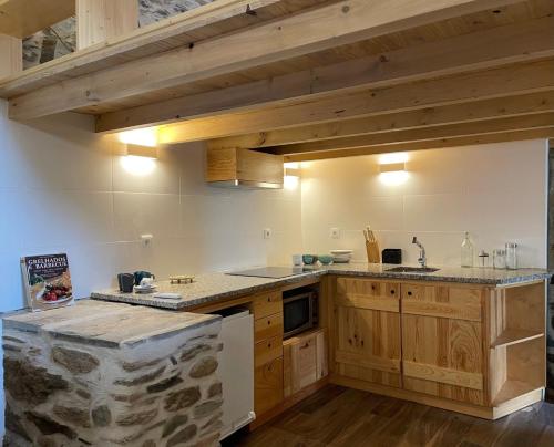 Sarzedasacalma - sesmo的厨房配有木制橱柜和石墙