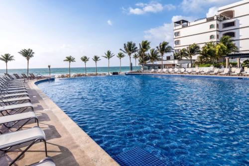 莫雷洛斯港Grand Residences Riviera Cancun, All Inclusive的一个带椅子的游泳池,背景是大海