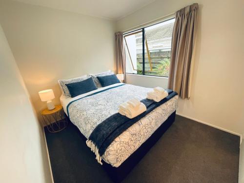 芒格努伊山Aintree On The Park的一间卧室配有一张带蓝色枕头的床和一扇窗户。