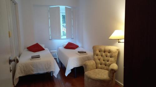 里斯本Pilar - Alfama River View的客房设有两张床、一把椅子和窗户。