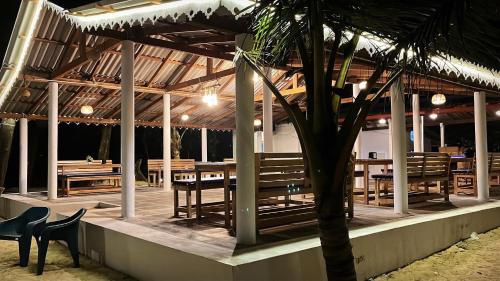 戈卡尔纳Vibes and Tides Beach Resort by Enlightened Vagabond的一间设有木桌和椅子的餐厅,并种植了棕榈树