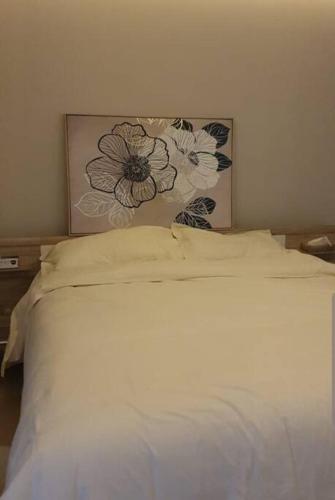 利雅德شقة خاصة برج رافال的一张白色的床,墙上挂着一幅花画