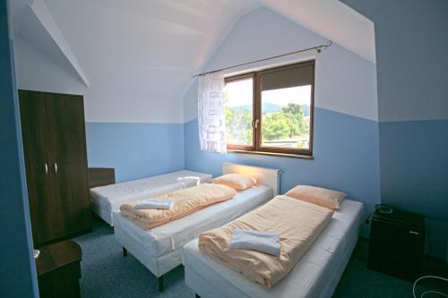 斯托尼拉斯奇Pensjonat Lew Jaskiniowy的蓝色客房的两张床,设有窗户