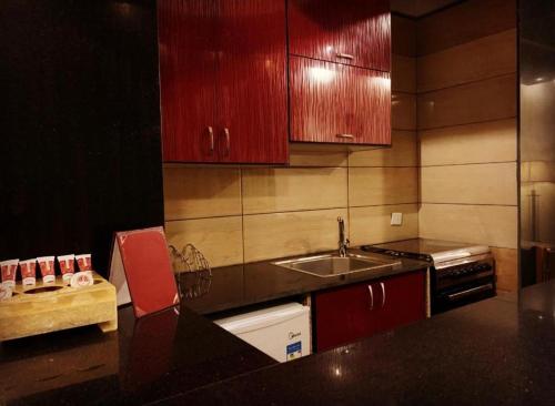 Qaryat al Bulushفندق بردى的一间带红色橱柜和水槽的厨房