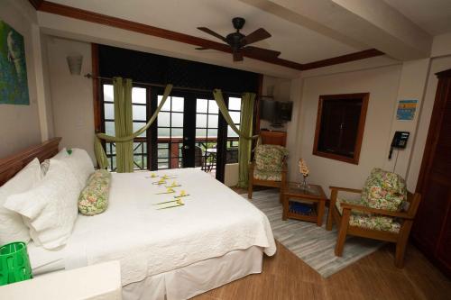苏弗里耶尔Samfi Gardens的卧室配有白色的床和吊扇