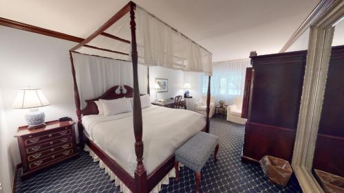 雅芳艾文老农场酒店的一间卧室配有一张天蓬床和梳妆台