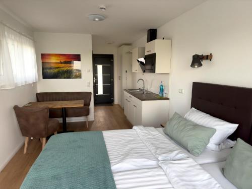 NidderauFernweg Apartments的一间卧室配有一张床铺和一张桌子,还设有一间厨房