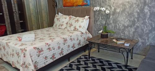 伊瓜苏Pousada Casa Bom Sono的一间卧室配有一张床和一张桌子,上面摆放着鲜花