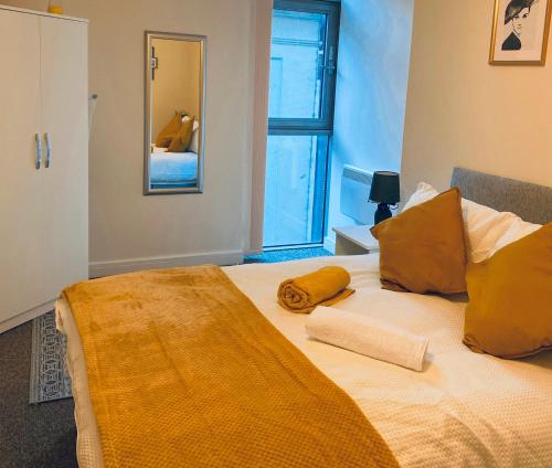 伯明翰stylish two bed in the heart of the city的一间卧室配有一张带黄色枕头的床和一扇窗户