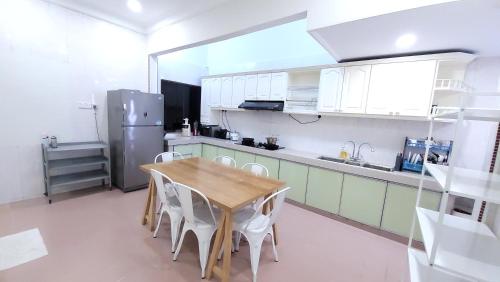 新山The Penggawa Homestay - 3 comfortable bedrooms的厨房配有木桌和白色橱柜。