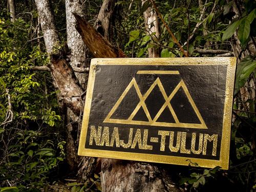 图卢姆Naajal Tulum Boutique Hotel - Magic & Jungle的树边的标志