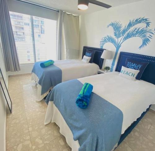 圣胡安KASA Royal Palms的酒店客房设有两张床,墙上挂着一棵棕榈树。