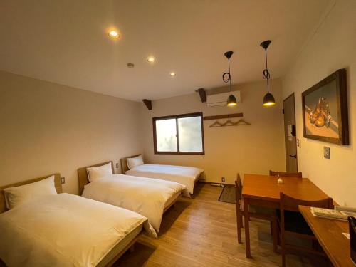 松本cafe&stay CASTANA的客房设有两张床、一张桌子和一张书桌。