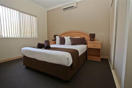 艾利斯斯普林斯托德爱丽丝公寓酒店的酒店客房设有一张大床和一个床头柜。