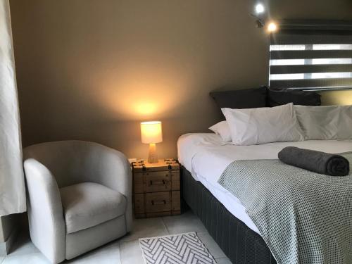 约翰内斯堡Aluve Guesthouse的一间卧室配有一张床、一把椅子和一盏灯