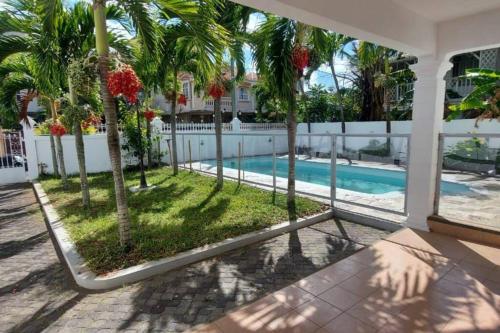 佩雷贝勒Villa Palmira 6 suites avec piscine 5 min à pied de la plage Pereybere的一座带游泳池和棕榈树的房子