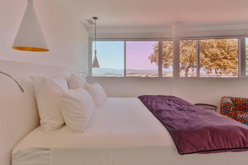 卡尔卡松Le Meez的白色的床、白色枕头和窗户
