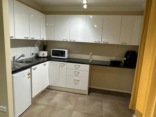 North TamborineOne bedroom studio的厨房配有白色橱柜和微波炉