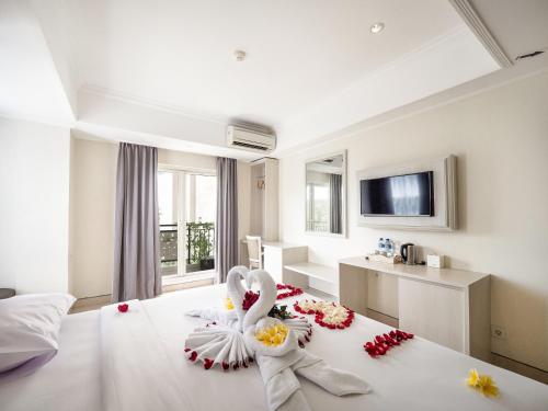 库塔Alron Hotel Kuta Powered by Archipelago的一间酒店客房,床上摆放着鲜花