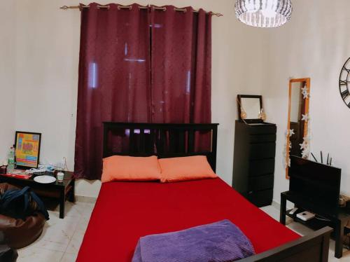 艾恩Full Apartment in Central Al Ain (All Amenities)的卧室在红色窗帘前配有红色的床
