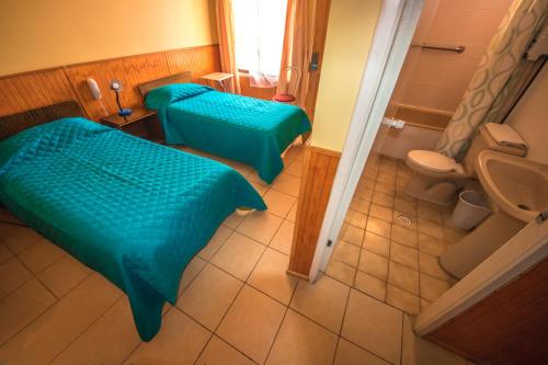 卡尔德拉Hotel Montecarlo的客房设有两张床和一间带卫生间的浴室。