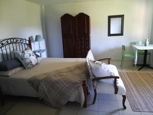戈登湾Crossroads Guestrooms的一间卧室配有一张床、一把椅子和一张桌子