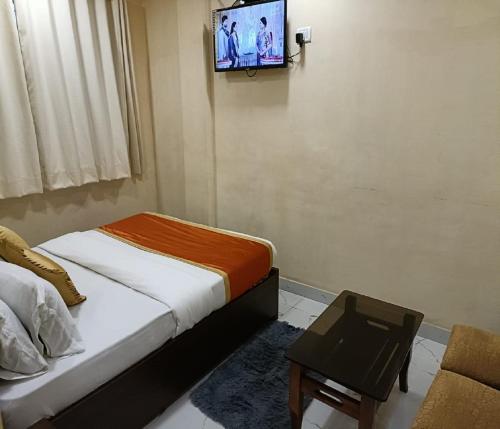 纳威孟买Hotel Royal Residency的卧室配有一张床,墙上配有电视。