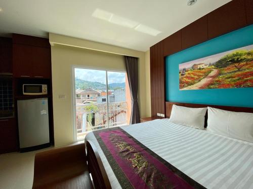 芭东海滩Baan Sudarat Hotel的一间卧室设有一张床和一个大窗户