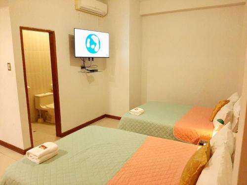 伊基托斯100 RV Apartments Iquitos-Apartamento primer piso con vista a piscina的客房设有两张床和一台墙上的电视。