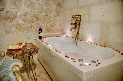 内夫谢希尔Mahperi Cappadocia Cave的客房内的白色浴缸,备有一瓶葡萄酒