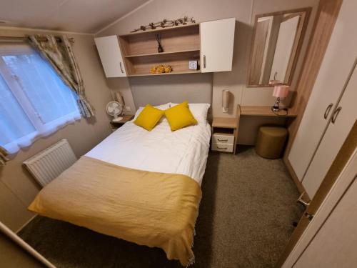 PrentegThe Beeches Holiday Home- based at Aberdunant Hall Holiday Park的一间小卧室,配有一张带黄色枕头的大床