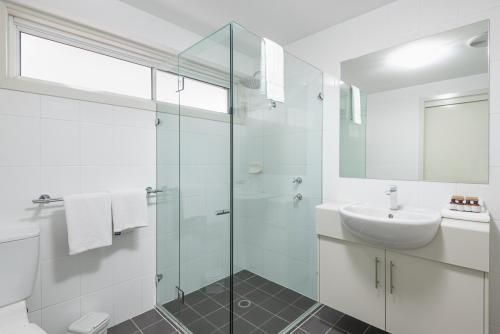 华纳海湾Warners Bay Apartments的白色的浴室设有水槽和玻璃淋浴间。