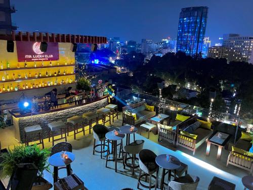 胡志明市Happy Life Grand Hotel & Sky Bar的享有带桌椅的屋顶酒吧的景致。