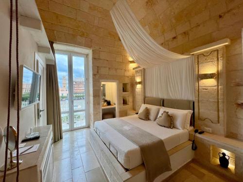 莫诺波利Vittorio Emanuele Charming Suites的一间卧室设有一张大床和一个大窗户