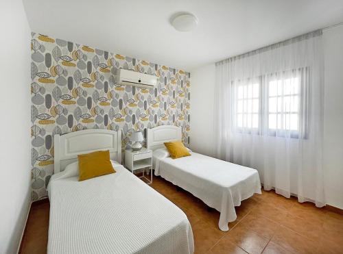 蒂亚斯Villa Charlotte的墙上的房间里设有两张白色的床
