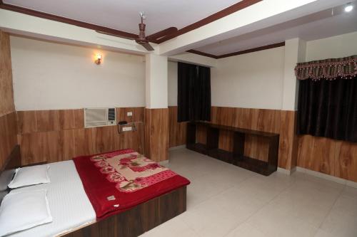 伯杰默里Jain Residency的一间卧室配有一张床铺,床上铺有红色毯子