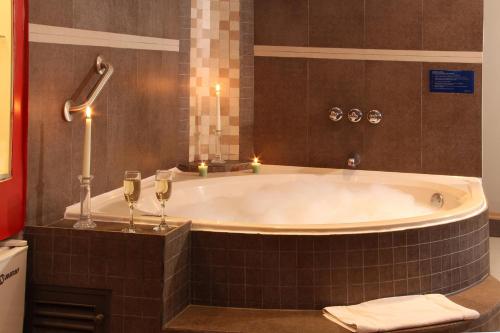 利马Los Mirtos suite & Hotel的浴缸配有两杯酒和蜡烛