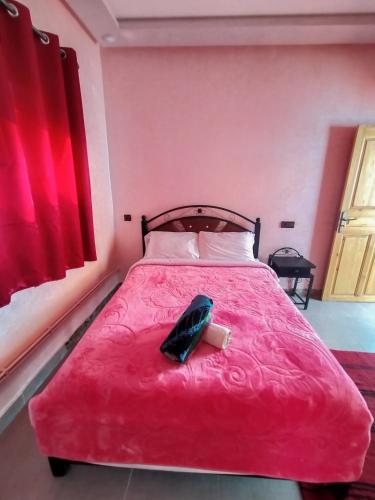 廷吉尔auberge restaurant tizgui的一间卧室配有一张红色的床,上面有电话