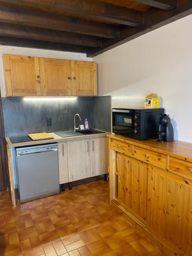 雷塞兹APPARTEMENT VUE SUR LES PISTES Aux SAISIES 4的厨房配有木制橱柜、水槽和微波炉