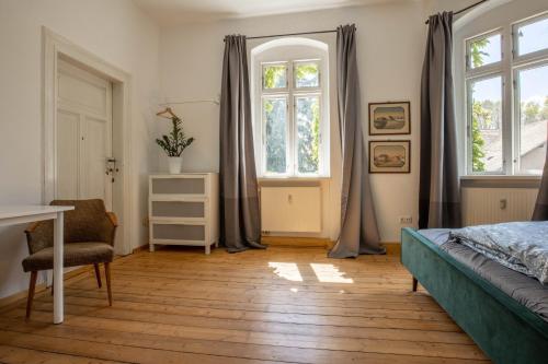 MügelnZeitreise: Wohnen im Herrenhaus genau zw. L u. DD的卧室配有一张床、一张书桌和窗户。