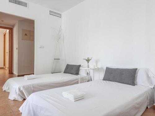 拉阿尔加瓦Alojamiento con piscina y parking en Sevilla的白色墙壁客房的两张床