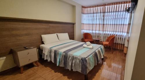 瓦努科Lembranças Hotel的一间卧室配有一张床、一张桌子和一个窗户。