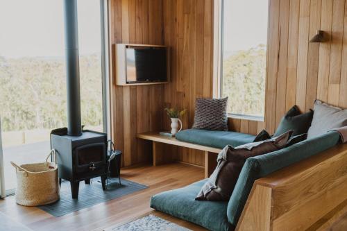 丹马克Upland Farm Luxury Cabins, Denmark Western Australia的带沙发和炉灶的客厅